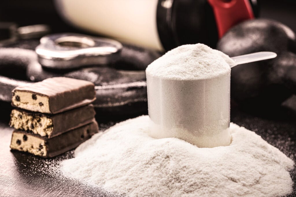 Kasein und Kaseinat-Pulver mit Messlöffel und Proteinriegeln – hochwertiges Milcheiweiß für Sportnahrung, Fitness und Muskelaufbau.