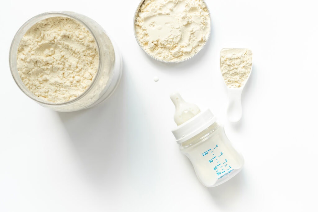 Dose mit Babynahrung und Babyflasche – Entmineralisiertes Molkenpulver ist eine hochwertige Zutat für Säuglingsnahrung.